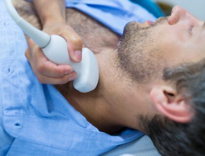 Man getting ultrasound of a thyroid from doctor in hospital Man getting ultrasound of a thyroid from doctor in hospital